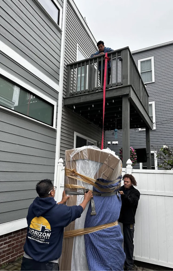 Horizon Boston Movers crew lowering a wrapped item from a deck